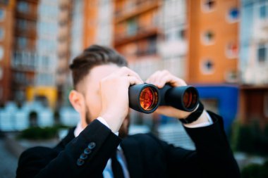 Açık havada rakipler üzerinde casusluk dürbün ile yakışıklı işadamı