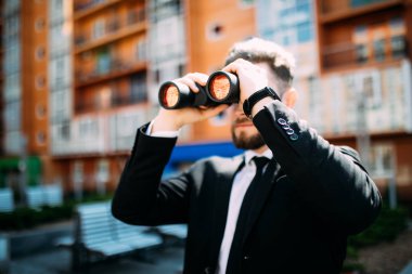 Açık havada building yakınındaki dürbünlü seyir yakışıklı iş adamı