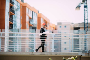 Başarı mühendis beyaz kask Emanet ve mavi baskı planları bina denetlemek için.
