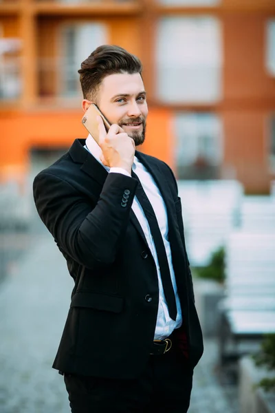 Bonito jovem homem de negócios andando na rua e falando em seu telefone — Fotografia de Stock