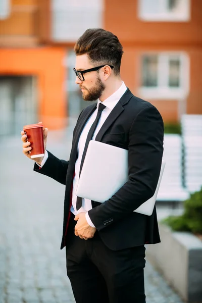 Affärsman i kostym med kaffe i handen gå med laptop i gata — Stockfoto