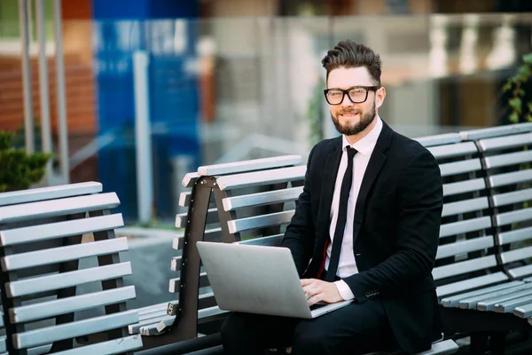 Bir modern şehir açık havada bankta oturmuş bir dizüstü bilgisayar yöneticisi