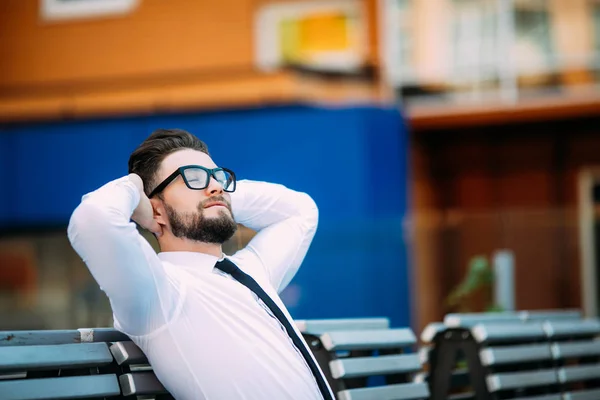 Rahat iş başının üzerine elle bir bankta oturan adam ve başarıdan sonra serbest zaman zevk — Stok fotoğraf