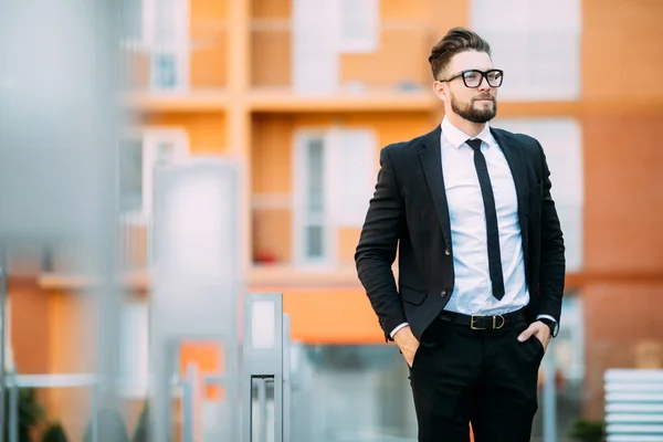 Stilig skäggiga affärsman i klassiska kostym tittar bort stående på balkongen i office center — Stockfoto