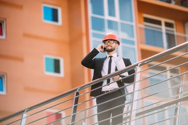 Planı inşaat yan cep telefonuyla konuşurken el ile mühendis.