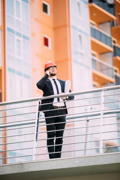 Planı inşaat yan cep telefonuyla konuşurken el ile mühendis.