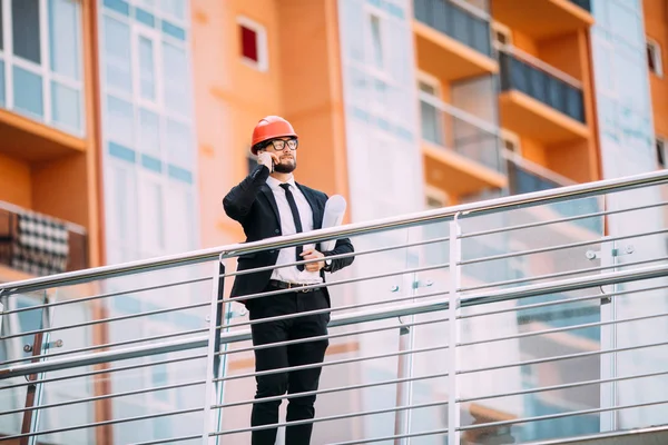 Planı inşaat yan cep telefonuyla konuşurken el ile mühendis.