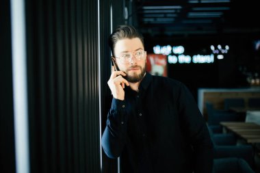 Office lobide duran, smartphone kullanarak genç işadamı.