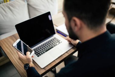 İşadamı mali bir app akıllı telefonunu kullanıyor ve raporlarda, eller dizüstü bilgisayar ile masasında yakın çekim