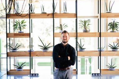 Modern ofisinde ayakta başarılı sakallı genç iş adamı