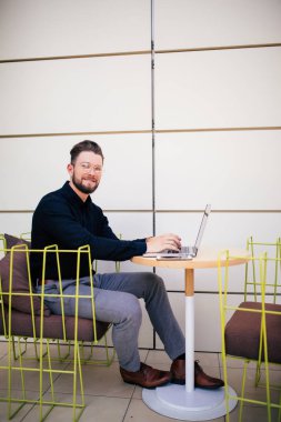 Yakışıklı adam laptop ve belgeler açık café'de çalışma