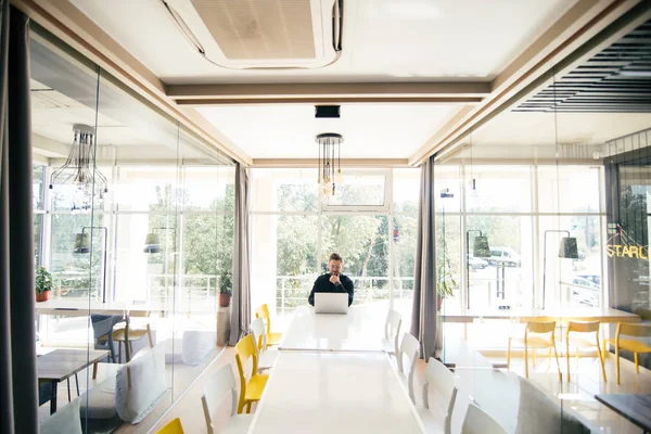 Skäggiga stilig affärsman sitta vid stora romm vitt konferensbord och arbeta på laptop innan mötet — Stockfoto