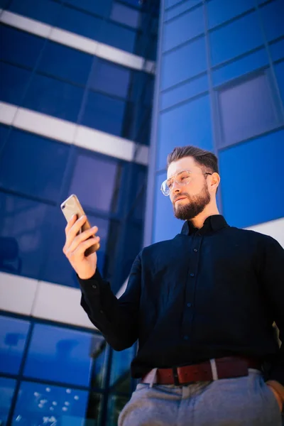 Happy usmívající se podnikatel pomocí moderní smartphone poblíž kanceláře, úspěšný zaměstnavatel uzavřít dohodu stoje u mrakodrapu úřadu — Stock fotografie