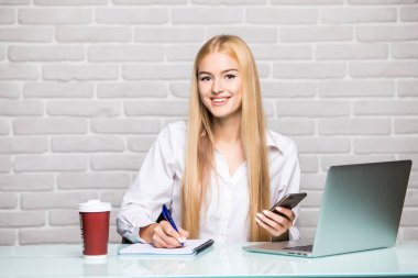 Genç bir iş portresi kadın kullanım telefon ve defter ofisinde fark olun