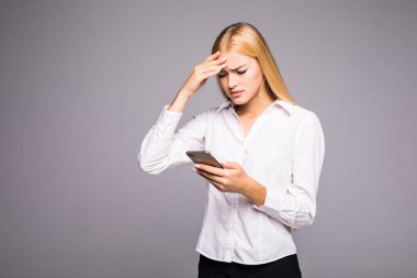 Çekici yorgun iş kadını bir smartphone kullanarak ve şakağına gri arka plan üzerine Masaj