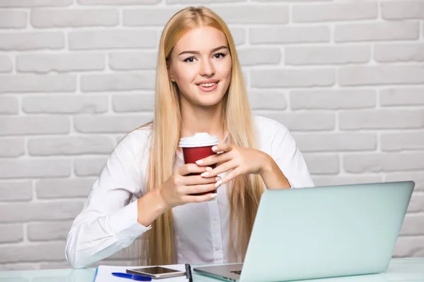 Atractiva mujer rubia de negocios trabajando en su computadora portátil y tomando café en su oficina — Foto de Stock