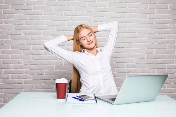 Affärskvinna sitter vid bordet i office och stretching hennes händer ovanför hennes huvud — Stockfoto