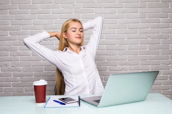 Affärskvinna sitter vid bordet i office och stretching hennes händer ovanför hennes huvud — Stockfoto