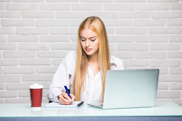 Retrato de una joven mujer de negocios usar el teléfono y hacer notar en el cuaderno en la oficina — Foto de Stock