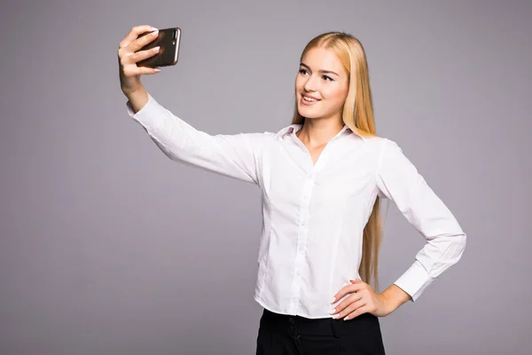 Mosolyogva így selfie fénykép smartphone üzletasszony. Szürke háttérrel áll — Stock Fotó