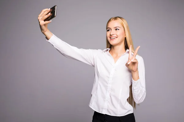 Mosolyogva így selfie fénykép smartphone üzletasszony. Szürke háttérrel áll — Stock Fotó