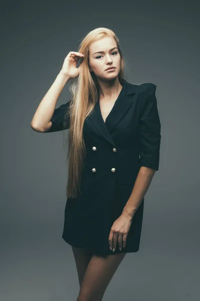 Hermosa modelo femenina en vestido negro sobre fondo gris — Foto de Stock