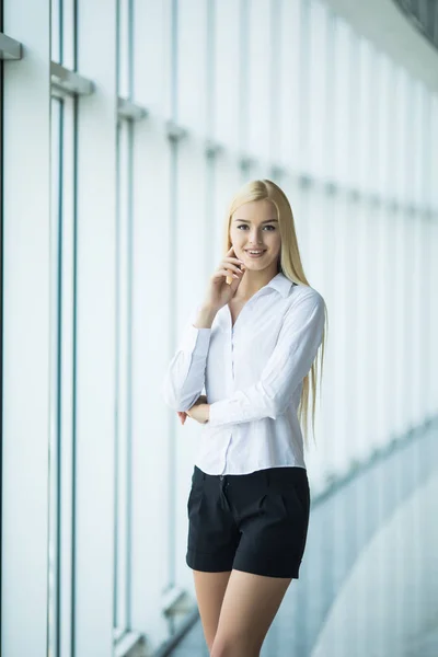 Eftertänksam kvinna ser in i kameran nära fönster — Stockfoto