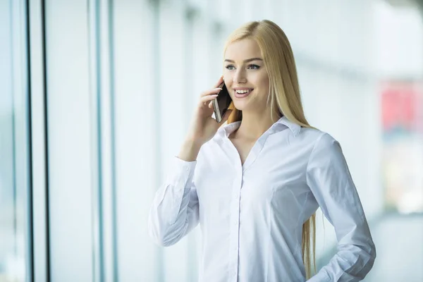 Donna d'affari parla telefono vicino a finestre panoramiche. Concetto di ufficio — Foto Stock