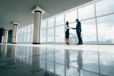 İşadamı ve Office büyük panoramik pencereler ile el sıkışan işkadını