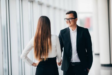 İşadamı ve Office ofis salonunda büyük panoramik pencereler ile el sıkışan işkadını