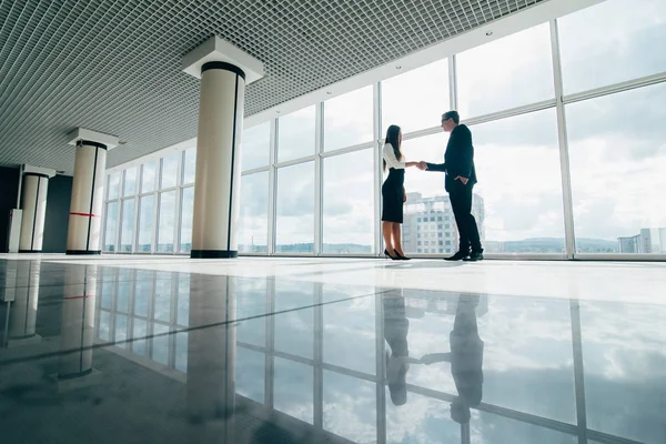 Homme d'affaires et femme d'affaires serrant la main au bureau avec de grandes fenêtres panoramiques — Photo