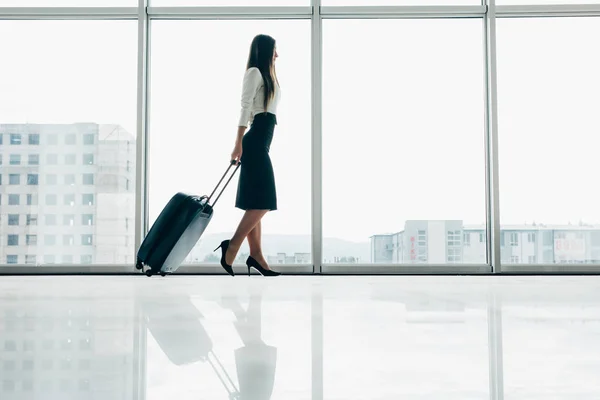 Viajante empresária esperando o voo atrasado no lounge do aeroporto de pé com bagagem assistindo asfalto na janela do aeroporto. Mulher no portão de embarque antes da partida . — Fotografia de Stock