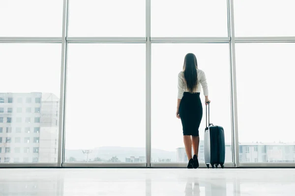 Bizneswoman podróżnik, czekając na opóźnione lotu na lotnisko salon stojący z bagażem oglądania asfalcie w Lotnisko okno. Kobieta przy wejściu do samolotu przed odlotem. — Zdjęcie stockowe
