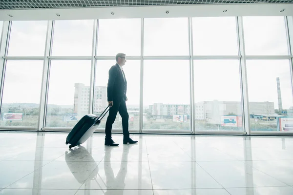 Affärsman promenader med vagnen och väska, affärsresor. Affärsman med väska i terminal gå till gate. — Stockfoto