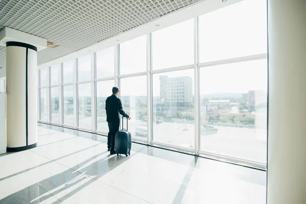 Biznesmen z walizką na lotnisko międzynarodowe bramce patrząc na latanie samolotem przez okna — Zdjęcie stockowe