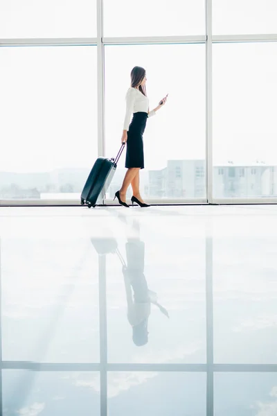 Empresária caminhando pelo aeroporto usando seu dispositivo de smartphone . — Fotografia de Stock