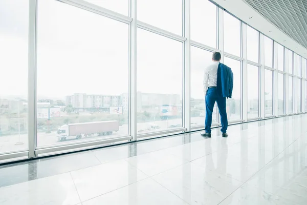 Jeune homme d'affaires avec veste sur les épaules dans les fenêtres panoramiques modernes du bureau — Photo