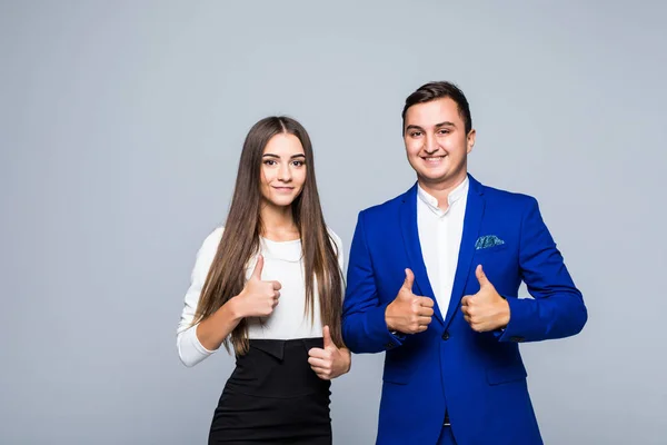Dos empresarios sonrientes confiados en ropa formal mostrando pulgares hacia arriba sobre fondo gris — Foto de Stock