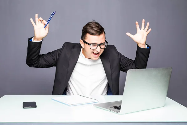 Homme d'affaires sénior en colère assis à son bureau et criant. Homme d'affaires en colère avec trop de travail au bureau. Beau jeune homme stressé dans des lunettes en utilisant un ordinateur portable — Photo