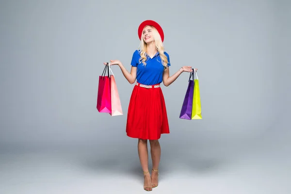 Een mooie jonge vrouw stijlvol gekleed in een hoed met zakken na het winkelen geïsoleerd — Stockfoto