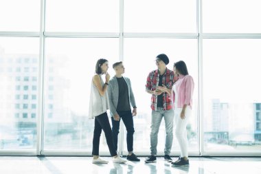 Başarılı dostu öğrenciler takım panoramik pencereler önünde yeni proje görüşüyorlar