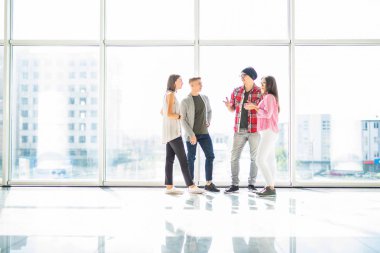 Panoramik pencereli aydınlık salonda konuşan dört arkadaşlar