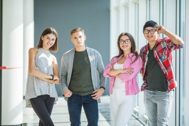 Ayakta ve kapalı gülümseyerek dört arkadaş. Ayak öğrenciler üniversitede.