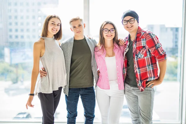 Groep van tiener jongens en meisjes is kijken camera, knuffelen en glimlachen terwijl permanent binnenshuis — Stockfoto