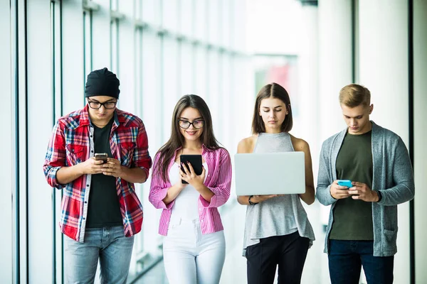 Felizes quatro amigos usando gadgets modernos dentro de casa — Fotografia de Stock