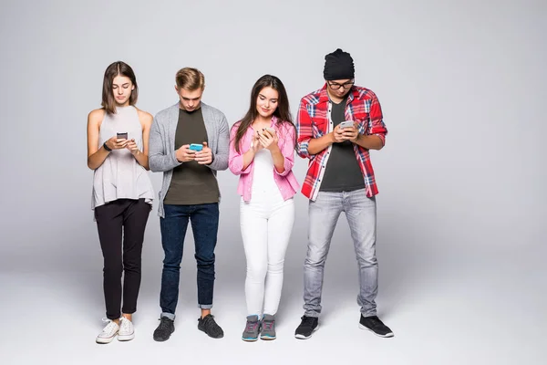 Quatro amigos usando gadget tecnologia telefone isolado no fundo cinza — Fotografia de Stock