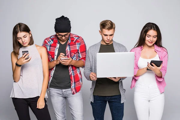 Groep van gelukkige jonge mensen zittend op de Bank en het gebruik van digitale tablet en laptop, geïsoleerd op witte achtergrond. — Stockfoto