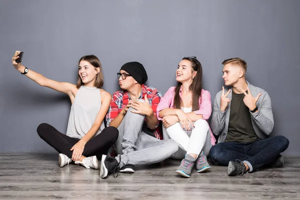 Amigos felizes tomando selfie enquanto sentados no chão — Fotografia de Stock