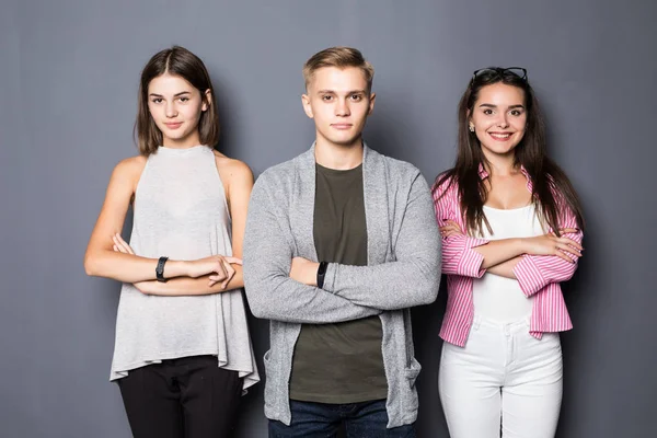 Felice giovani amici in piedi in casa su sfondo grigio — Foto Stock