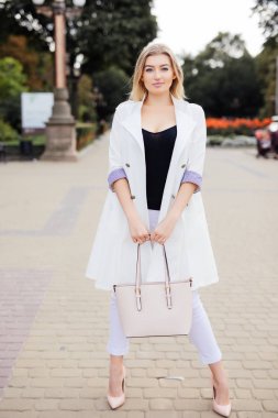 Sokakta merdivenlerde beyaz ceketli bir modeldir.